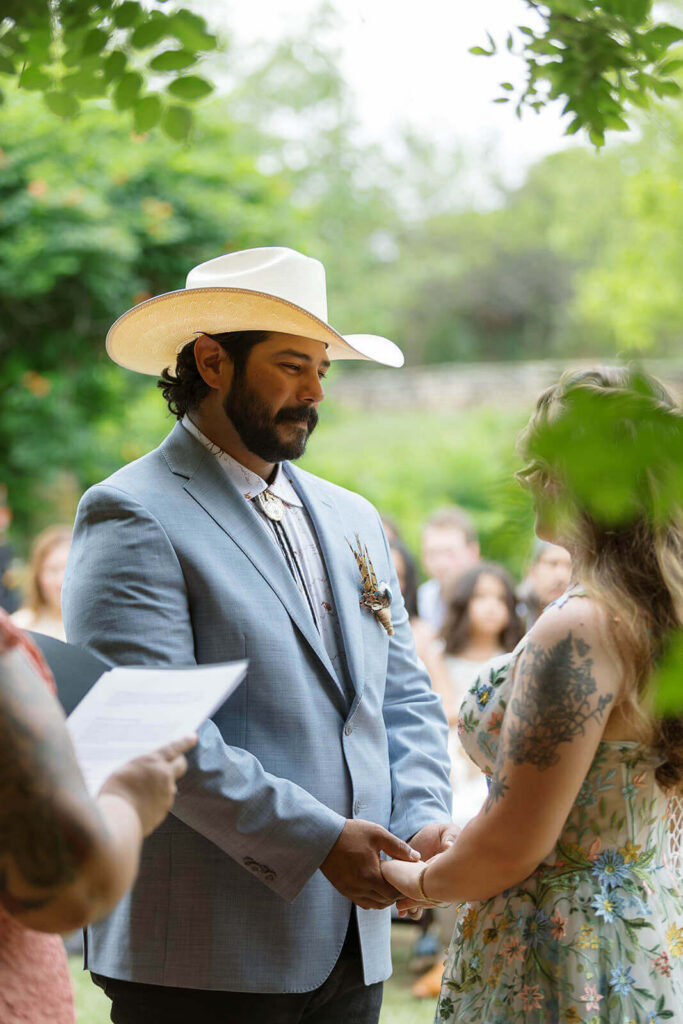 Close up photo of groom in cowboy hat smiling at bride
