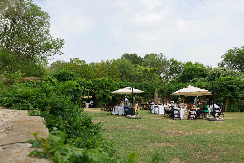 Wide view of tables and chairs setup for amphitheater reception surrounded by trees and vines