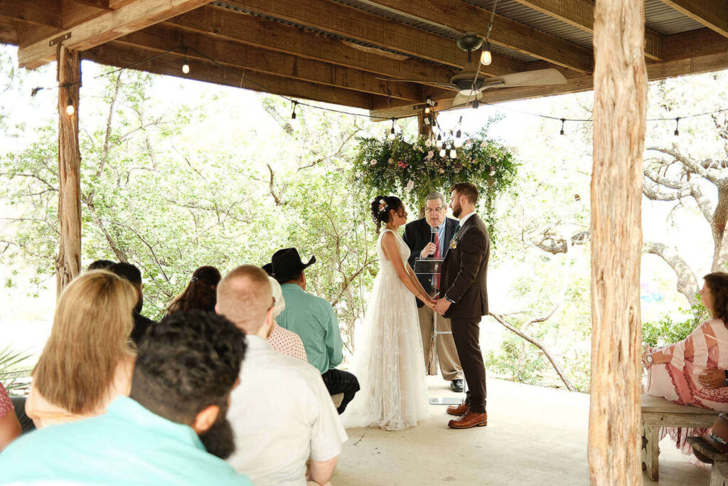 Bride and groom holding hands at the altar of their wedding ceremony on the patio of Auld House at San Antonio Botanical Garden