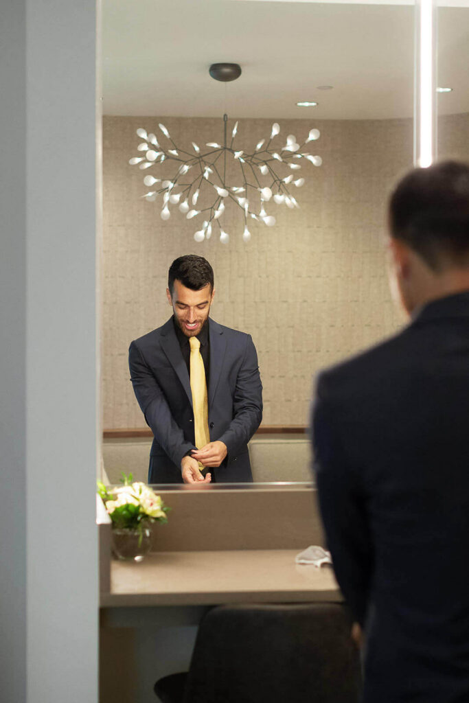 A groom putting on his cufflinks inside the getting ready room at Betty Kelso Center at The San Antonio Botanical Garden