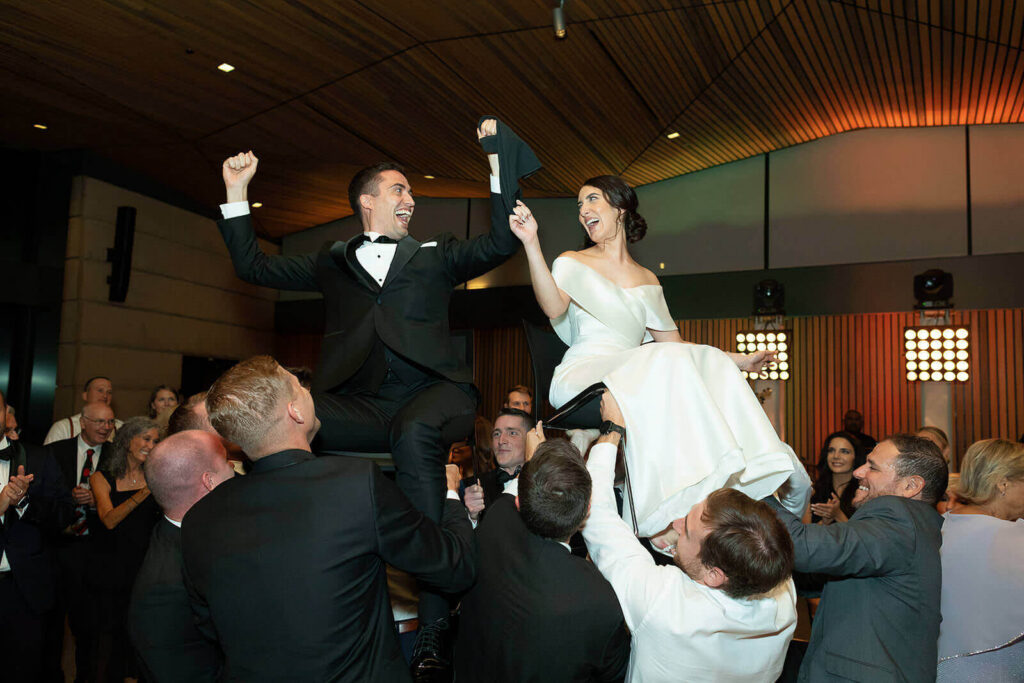 Bride and groom hoisted on chairs during the hora at Betty Kelso Center