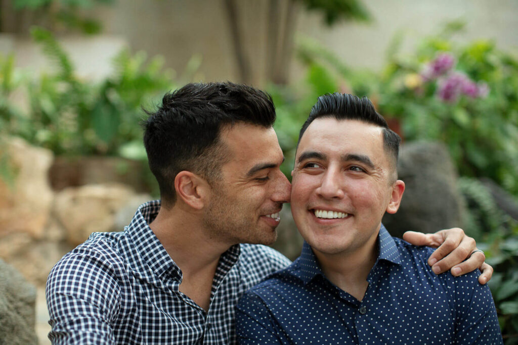Close up of a gay couple giggling inside the Gretchen Northrup Tropical Conservatory