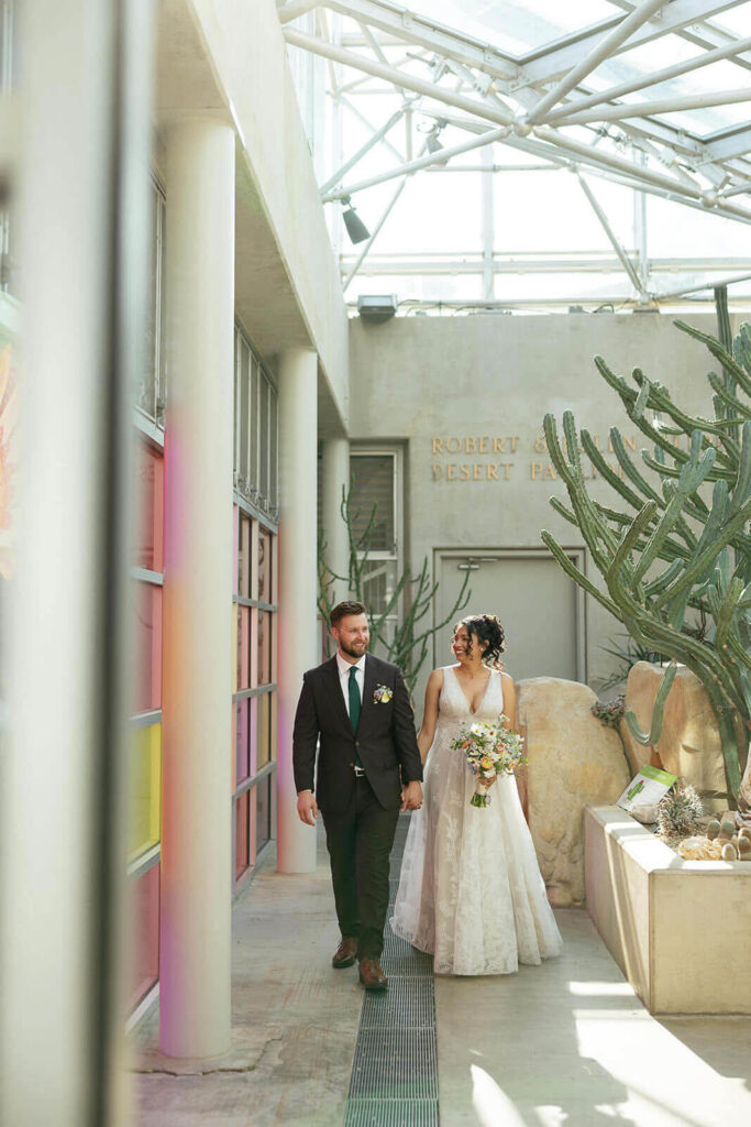 Bride and groom walking along wall inside the desert pavilion at San Antonio Botanical Garden