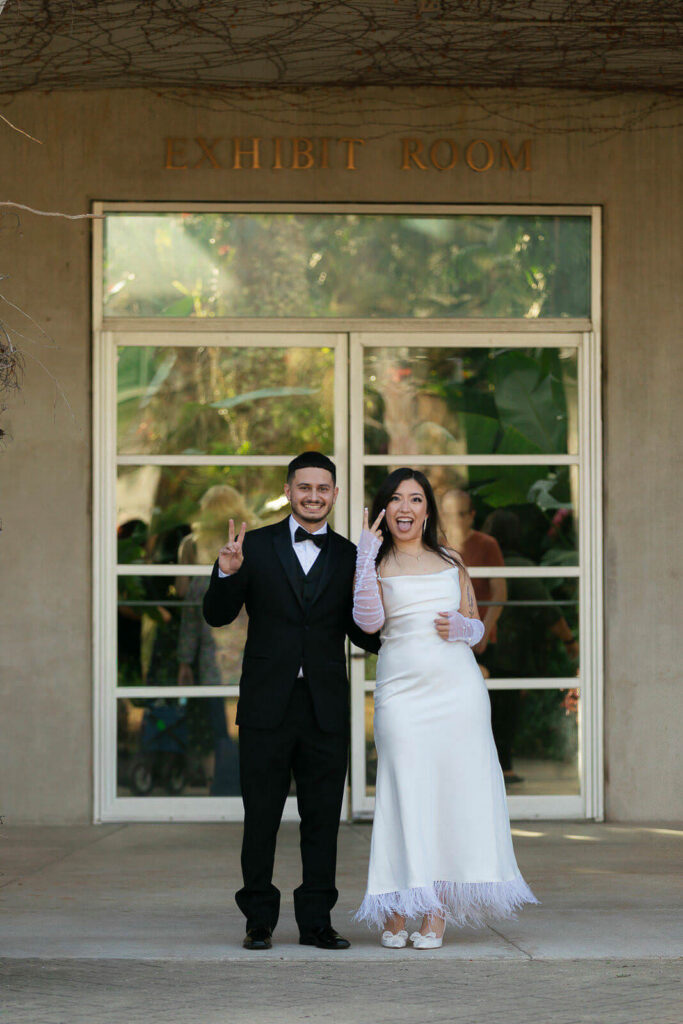 Couple holding up peace signs and laughing at their Lucile Halsell Conservatory wedding ceremony