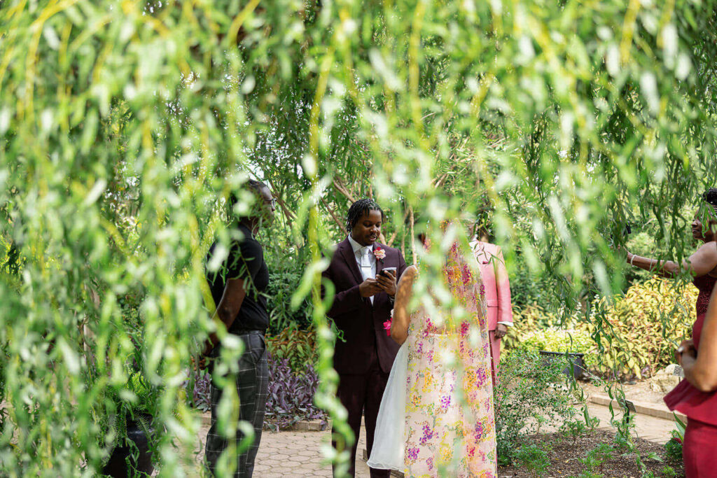 Groom reading his vows to his bride, framed by bright green willow branches