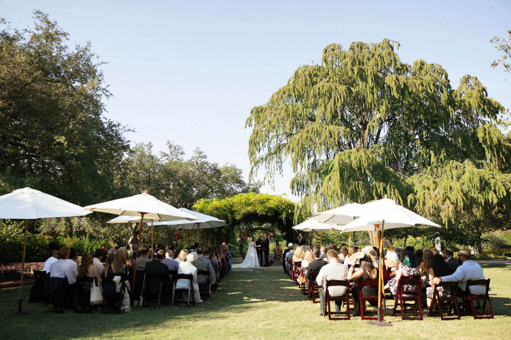 A wedding ceremony on Greehey lawn in front of Wisteria Arbor